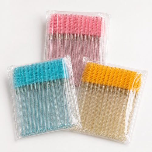 Disposable glitter-handle spoolie brushes in sealed pink, blue and yellow packs